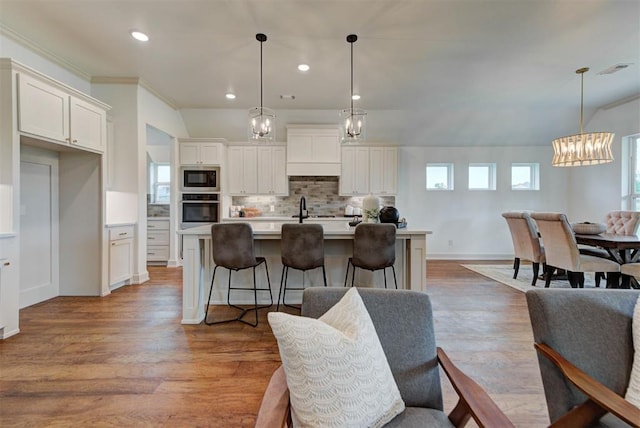 14500 Rushing Ln, Edmond, OK 73025 - kitchen with stainless steel oven, built in microwave, a chandelier, decorative backsplash, and a center island with sink