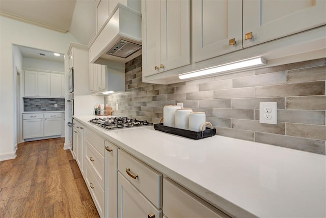 14500 Rushing Ln, Edmond, OK 73025 - kitchen with custom exhaust hood, appliances with stainless steel finishes, light countertops, white cabinetry, and backsplash