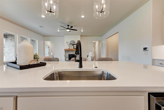 14500 Rushing Ln, Edmond, OK 73025 - kitchen featuring a sink, a stone fireplace, a chandelier, ornamental molding, and open floor plan
