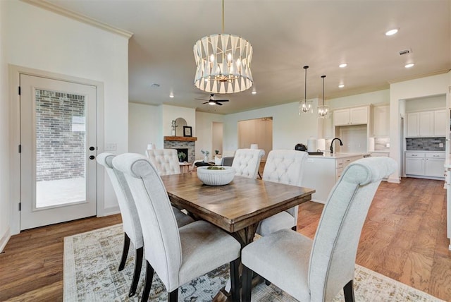 14500 Rushing Ln, Edmond, OK 73025 - dining space featuring a chandelier, wood finished floors, recessed lighting, a fireplace, and a ceiling fan