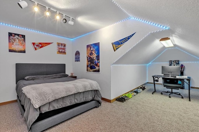 carpeted bedroom with vaulted ceiling, a textured ceiling, and track lighting