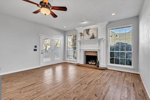 unfurnished living room with ceiling fan, a fireplace, and light hardwood / wood-style flooring