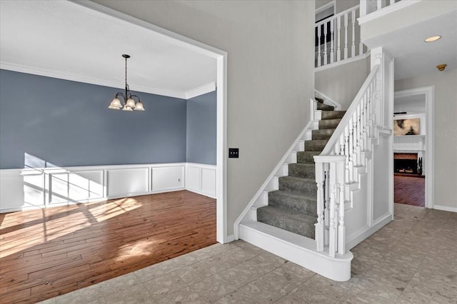 staircase featuring crown molding, a chandelier, and hardwood / wood-style flooring