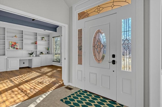 entryway featuring dark hardwood / wood-style flooring, built in desk, and vaulted ceiling