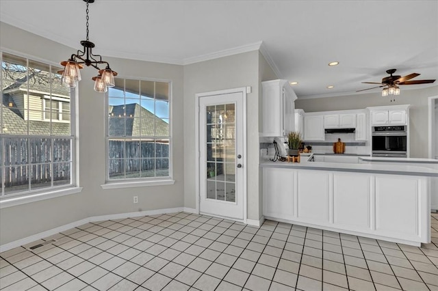 kitchen with stainless steel oven, ornamental molding, kitchen peninsula, pendant lighting, and white cabinets