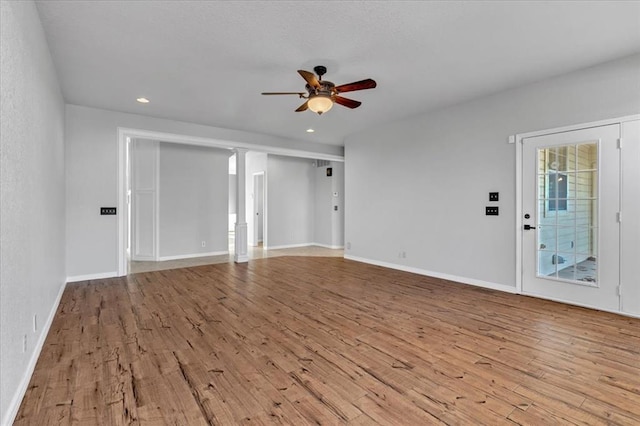 empty room with light hardwood / wood-style flooring, decorative columns, and ceiling fan