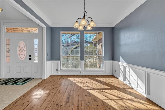 interior space with a notable chandelier, crown molding, and light wood-type flooring