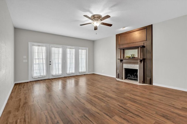 unfurnished living room featuring hardwood / wood-style flooring, ceiling fan, and a fireplace