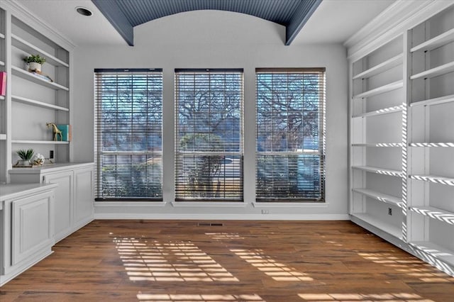 unfurnished dining area with dark wood-type flooring, lofted ceiling, and built in features