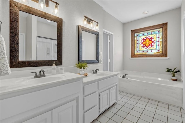 bathroom with tile patterned flooring, vanity, and a bath