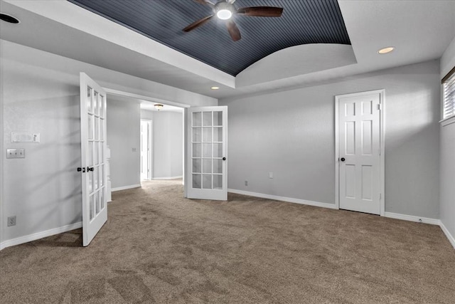 empty room with french doors, ceiling fan, a raised ceiling, and carpet