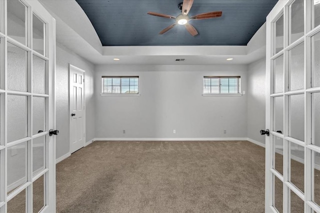 spare room featuring ceiling fan, carpet floors, french doors, and a raised ceiling