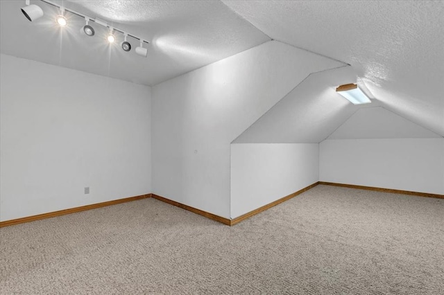 additional living space featuring lofted ceiling, carpet flooring, and a textured ceiling