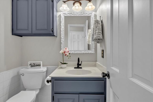 bathroom featuring vanity, tile walls, and toilet