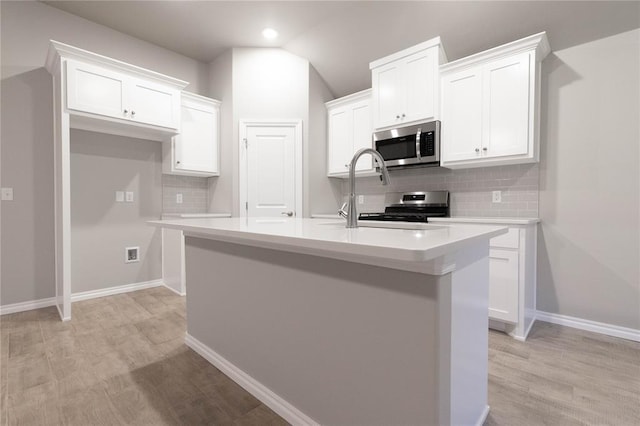 12333 SW 30th St, Yukon, OK 73099 - kitchen with appliances with stainless steel finishes, decorative backsplash, a kitchen island with sink, white cabinets, and lofted ceiling
