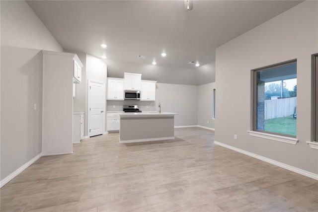 12333 SW 30th St, Yukon, OK 73099 - kitchen featuring appliances with stainless steel finishes, open floor plan, light wood-type flooring, white cabinets, and an island with sink