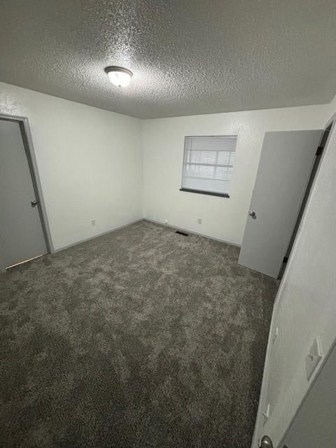 carpeted spare room featuring a textured ceiling