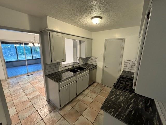 kitchen featuring decorative backsplash, stainless steel dishwasher, a textured ceiling, sink, and light tile patterned flooring