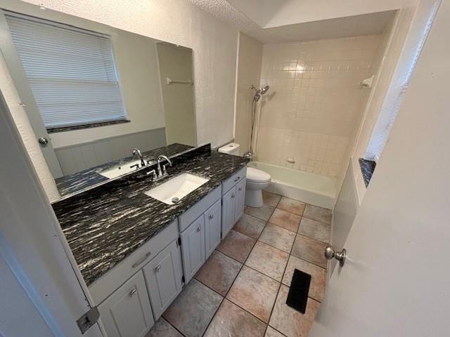 full bathroom with tile patterned flooring, vanity, tiled shower / bath combo, and toilet