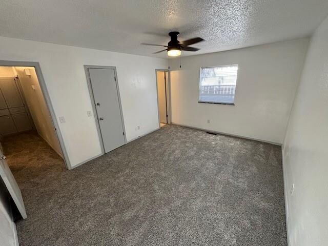 unfurnished bedroom featuring ceiling fan, carpet floors, and a textured ceiling