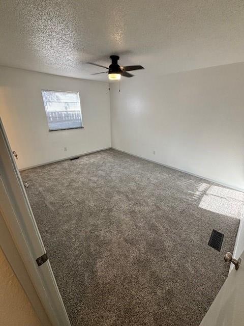 carpeted spare room with a textured ceiling and ceiling fan