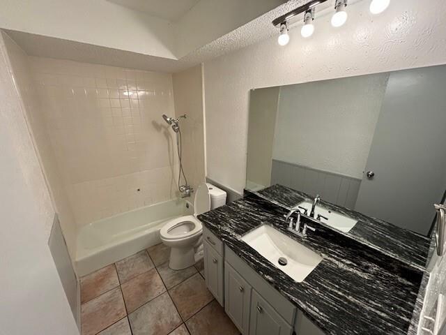 full bathroom with toilet, vanity, tile patterned floors, and tiled shower / bath