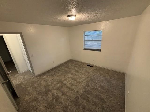 empty room with carpet and a textured ceiling