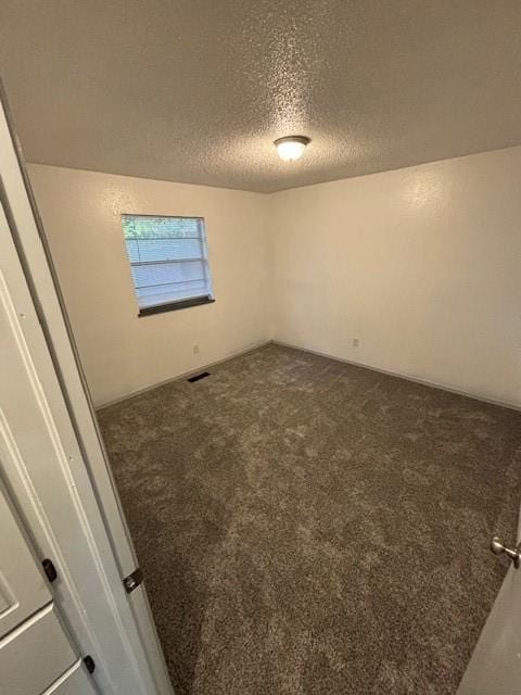 unfurnished room featuring dark colored carpet and a textured ceiling