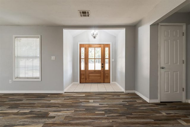 foyer with a chandelier, dark wood-type flooring, and vaulted ceiling