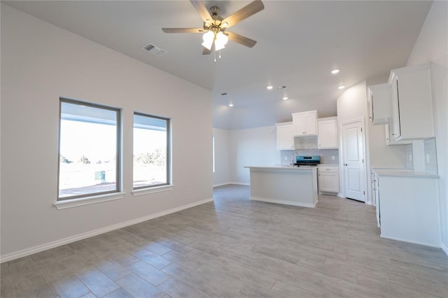 kitchen with visible vents, ceiling fan, open floor plan, white cabinetry, and backsplash