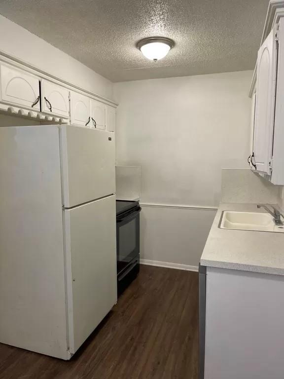 kitchen with black range with electric stovetop, sink, dark hardwood / wood-style floors, white refrigerator, and white cabinets