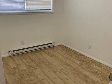 spare room with baseboard heating and light hardwood / wood-style flooring