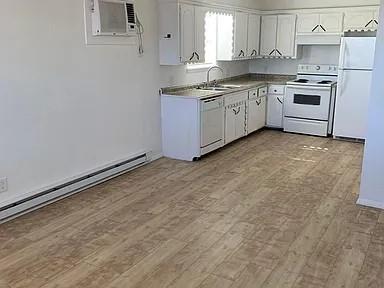 kitchen with white appliances, light hardwood / wood-style flooring, white cabinetry, and sink