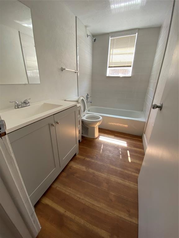 full bathroom with hardwood / wood-style floors, vanity, toilet, and tiled shower / bath