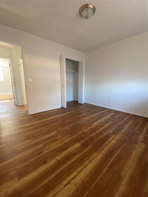 unfurnished bedroom with a closet and dark wood-type flooring