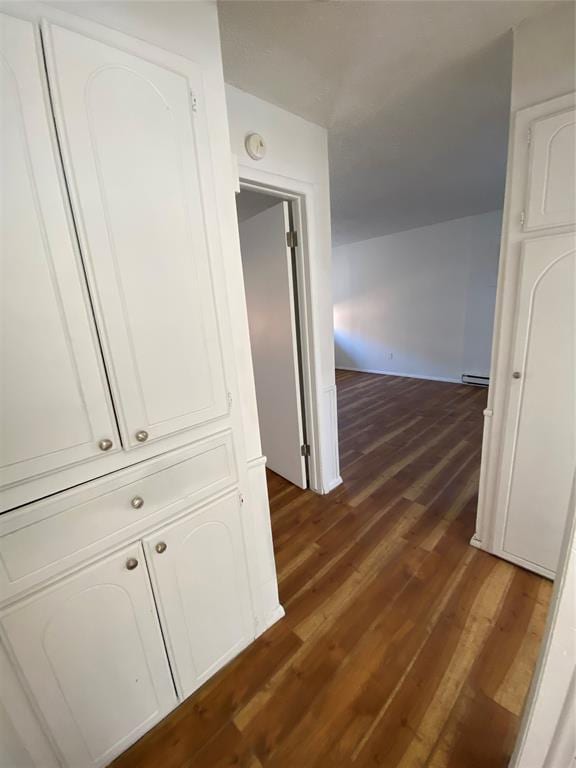 corridor with dark hardwood / wood-style flooring and a baseboard heating unit