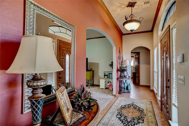 foyer entrance featuring crown molding, light tile patterned floors, and lofted ceiling