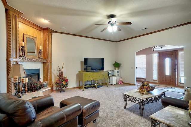 living room featuring carpet flooring, ceiling fan, ornamental molding, and a textured ceiling