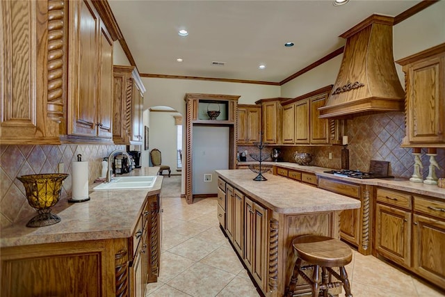 kitchen featuring backsplash, a breakfast bar, custom range hood, sink, and a center island