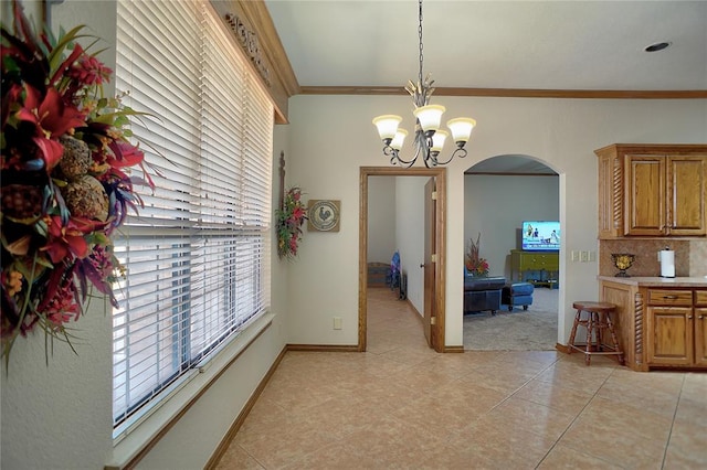 dining area with light tile patterned floors, ornamental molding, and a notable chandelier