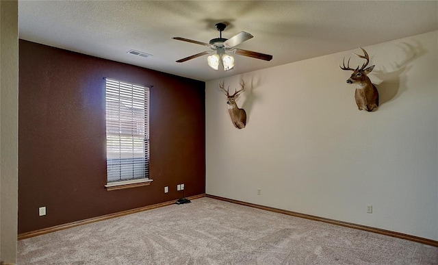 empty room with ceiling fan, light colored carpet, and a textured ceiling