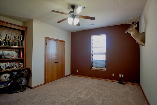 unfurnished bedroom with ceiling fan, light colored carpet, and a closet