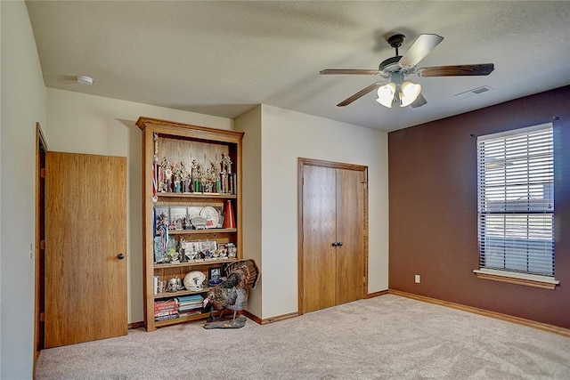 unfurnished bedroom with a textured ceiling, light colored carpet, and ceiling fan