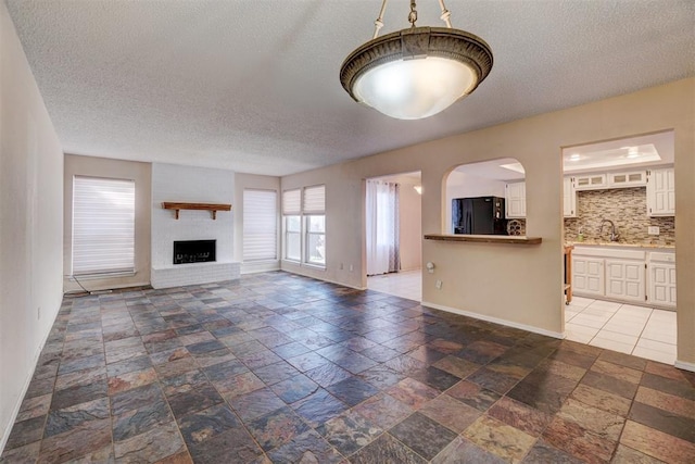 unfurnished living room featuring a textured ceiling, sink, and a fireplace