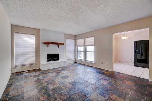 unfurnished living room featuring a textured ceiling and a brick fireplace