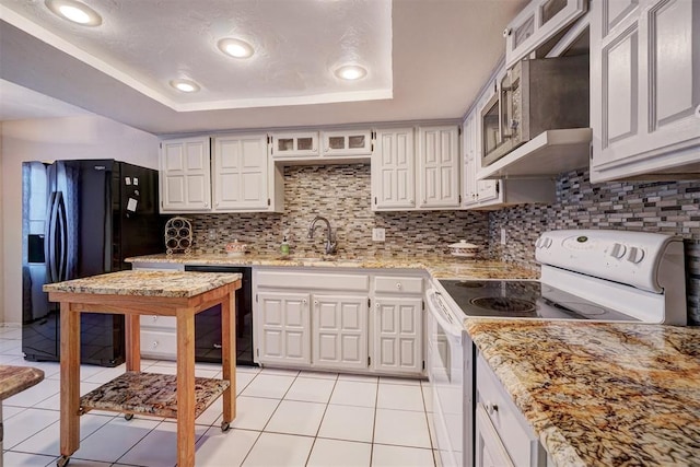 kitchen featuring a raised ceiling, white cabinetry, sink, and black appliances