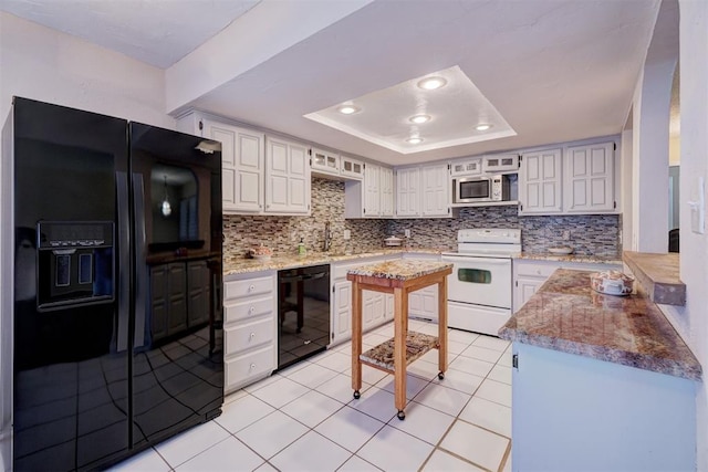 kitchen with backsplash, black appliances, white cabinets, light tile patterned floors, and a tray ceiling