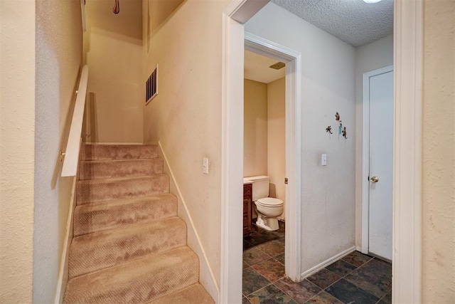 stairway featuring a textured ceiling