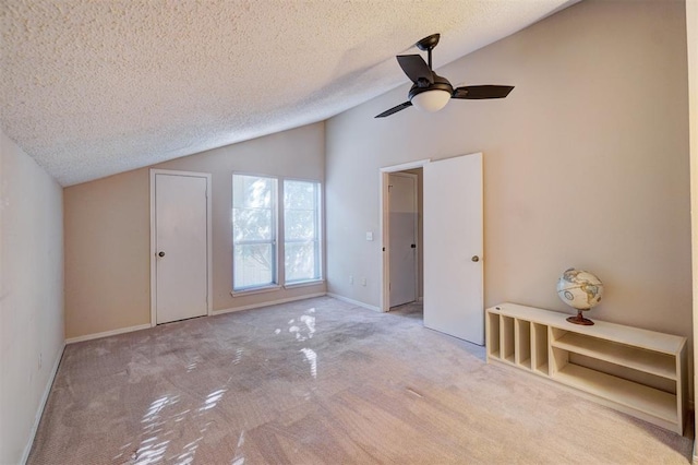 unfurnished room featuring light carpet, a textured ceiling, ceiling fan, and lofted ceiling