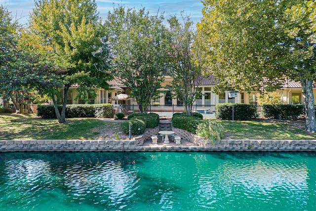 view of pool featuring a water view, fence, and a yard